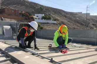 Two people install solar panels on a roof in Mexico