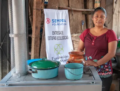 A community member stands next to her new stove