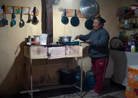 A woman cooks on an improvised stove in Mexico