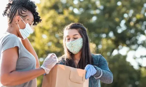 Two women volunteering to serve food and wearing masks