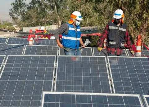 Team members install solar panels on a roof in Mexico